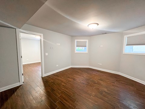 A room with wooden floors and a window with blinds.