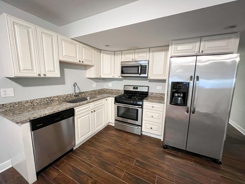 A kitchen with white cabinets and a granite countertop.