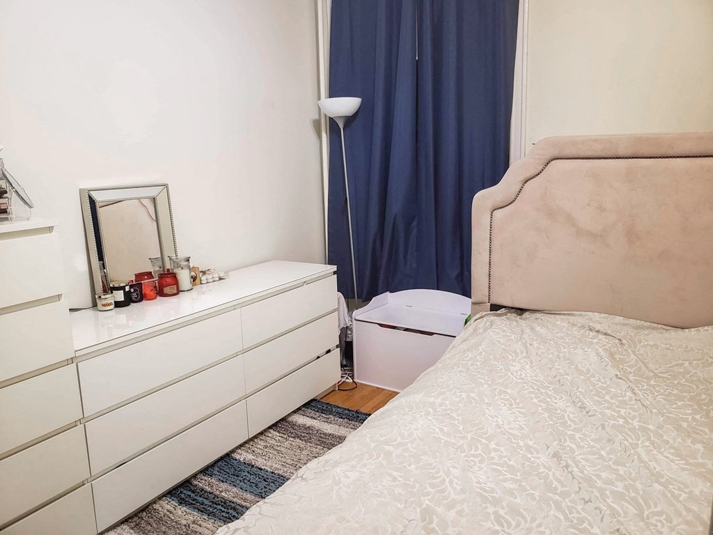 a small bedroom with a bed and a dresser with a mirror