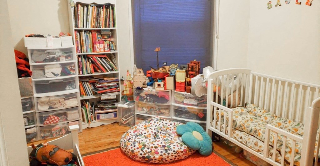 a nursery with a crib and a book shelf and a window