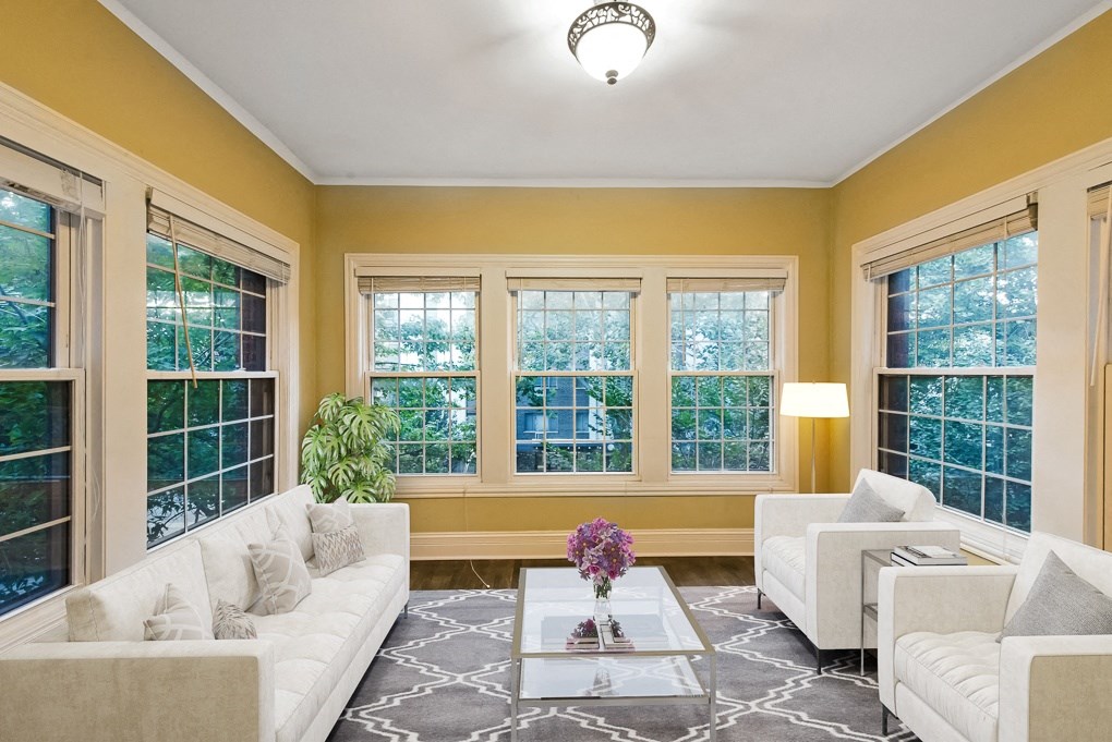 a living room with yellow walls and white furniture and windows