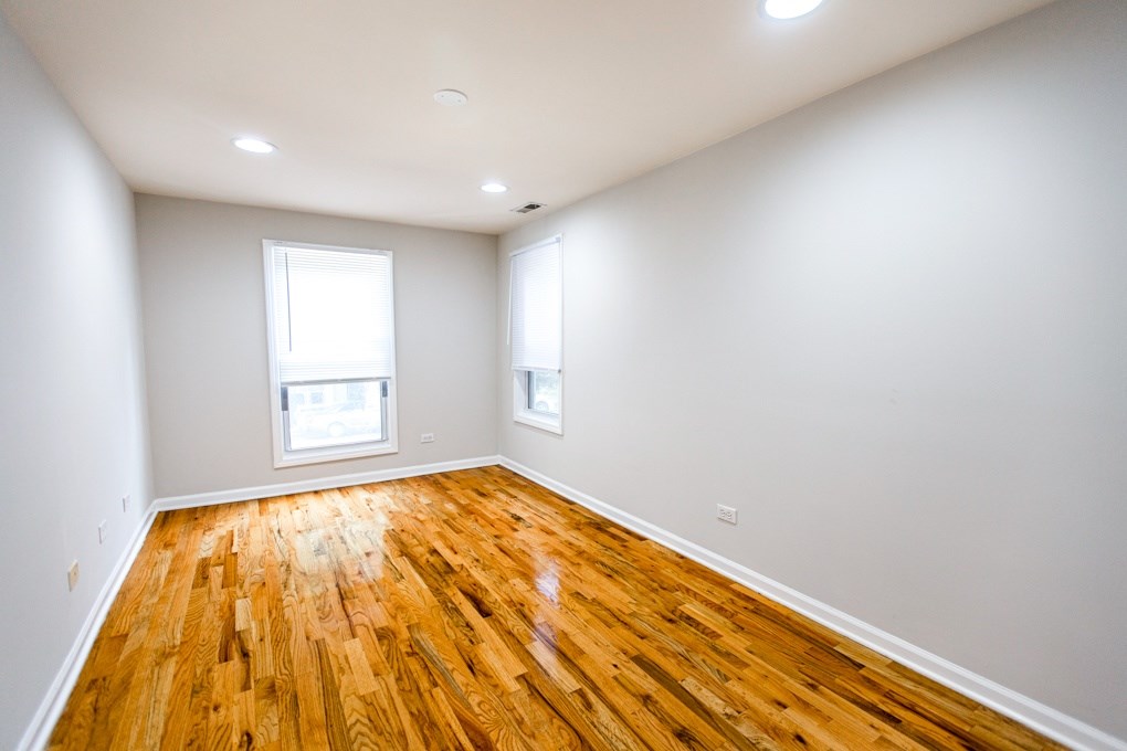 A room with wooden floors and two windows.