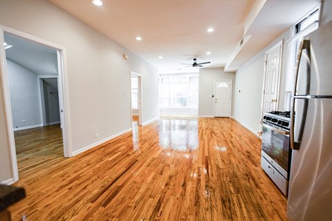 A kitchen with a wooden floor and a refrigerator on the right side.