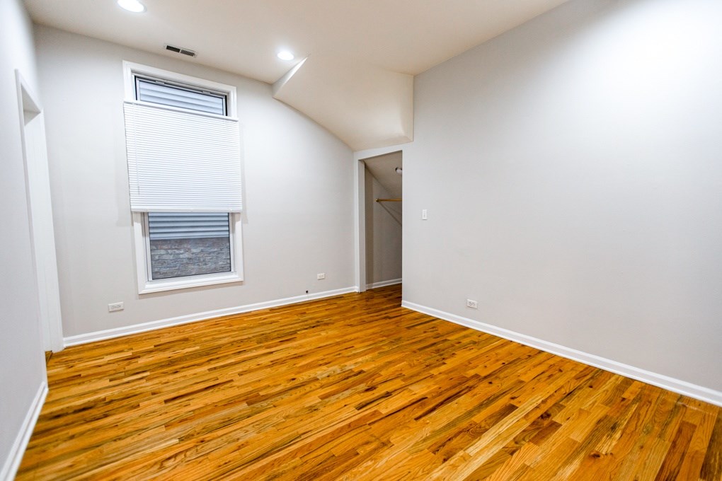A room with wooden floors and a window with blinds.
