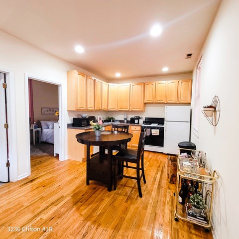 A kitchen with wooden floors and a table with a vase of flowers on it.