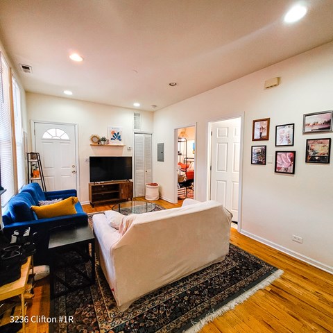 A living room with a couch, a chair, a coffee table, a fireplace, and pictures on the wall.