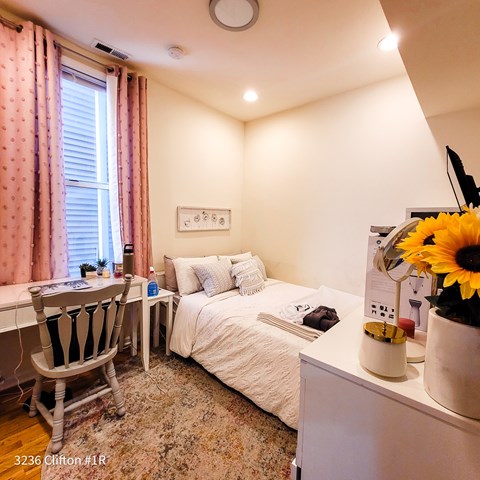 A bedroom with a bed, desk, and chair.