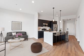 a living room and kitchen area with white walls and hardwood floors
