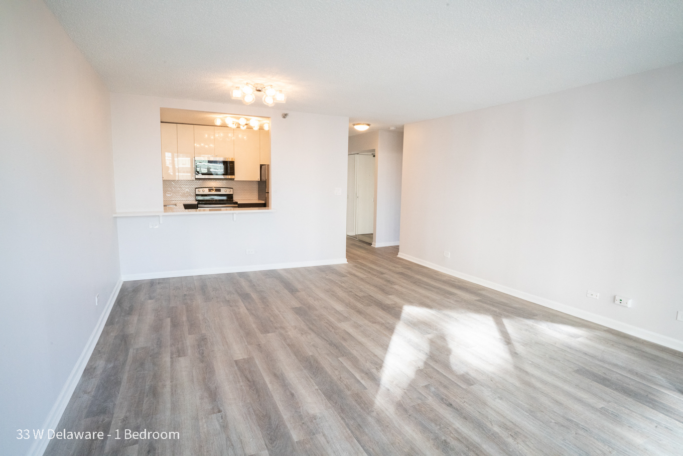 a spacious living room with white walls and wood flooring