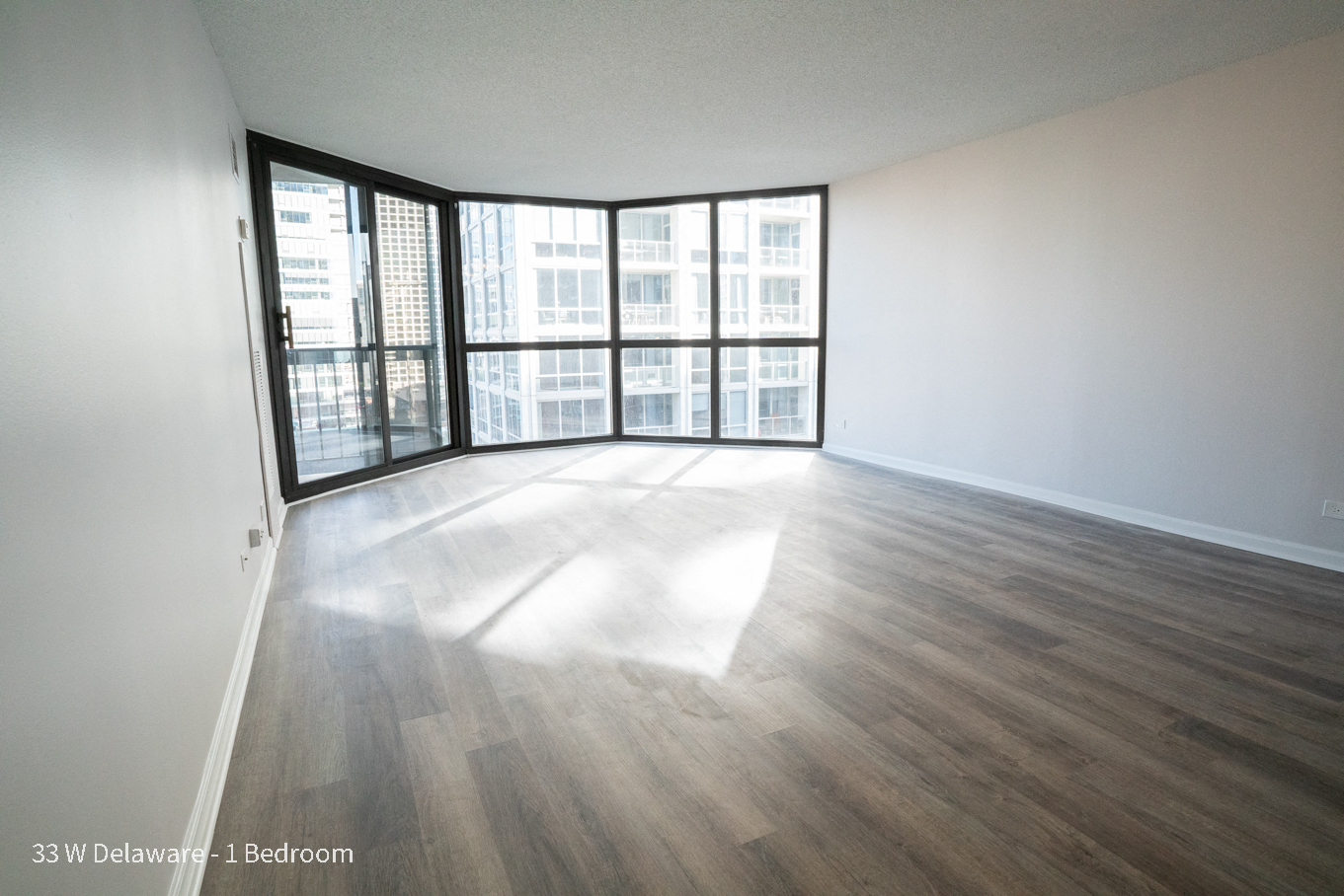 an empty living room with wood flooring and a large window