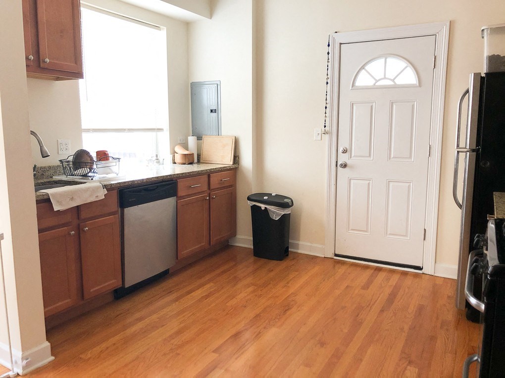 A kitchen with wooden floors and a white door.