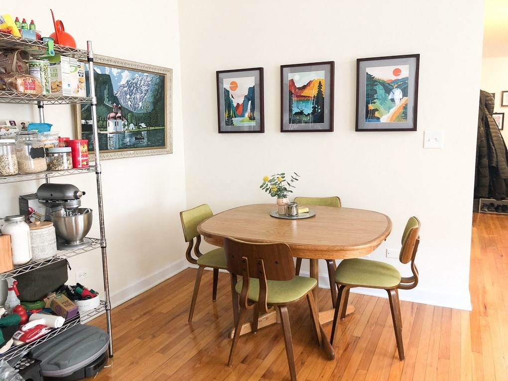 A dining room with a table and chairs and pictures on the wall.