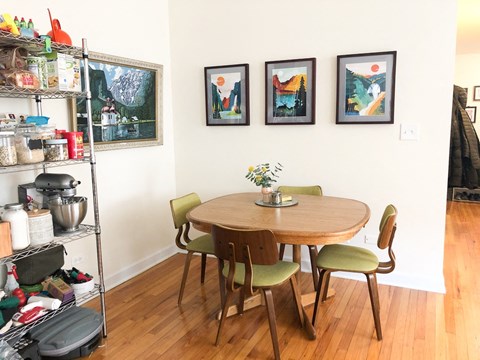 A dining room with a table and chairs and pictures on the wall.