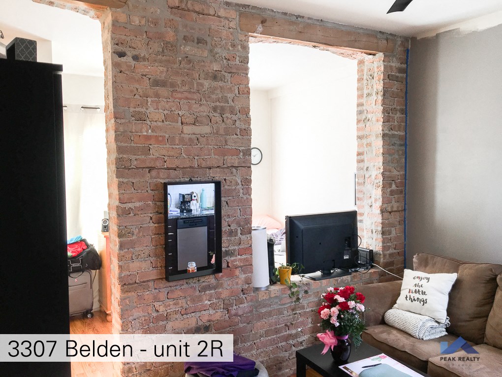 a living room with a brick fireplace and a television