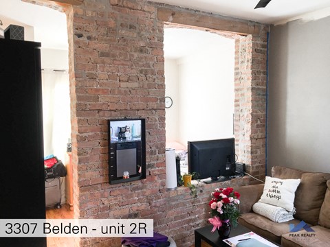 a living room with a brick fireplace and a television