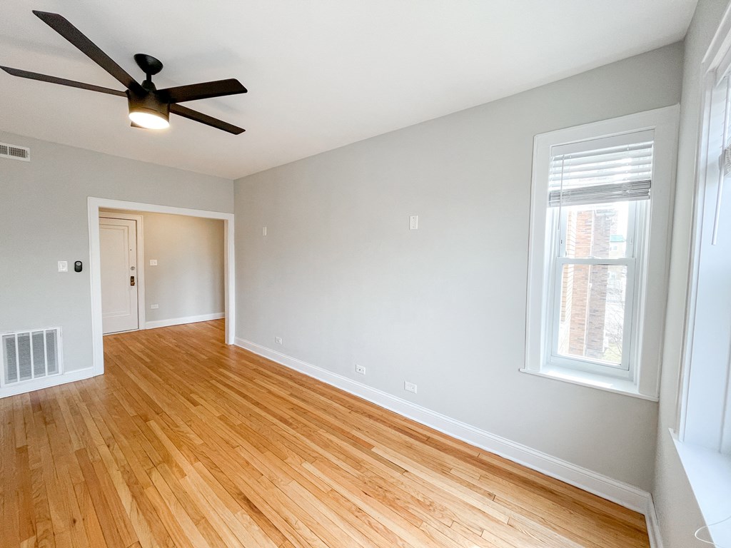 an empty living room with wood floors and a ceiling fan