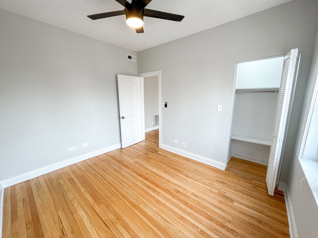an empty living room with wood flooring and a ceiling fan