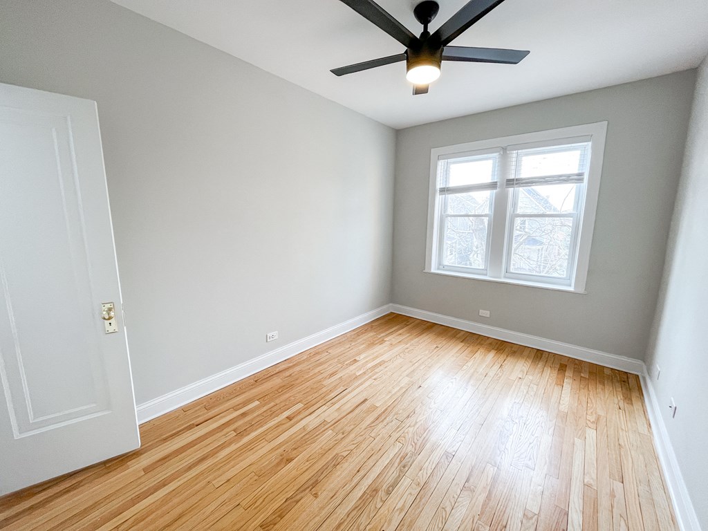 an empty room with wood floors and a ceiling fan