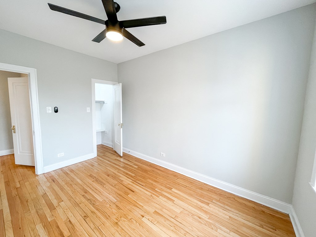 an empty living room with wood floors and a ceiling fan