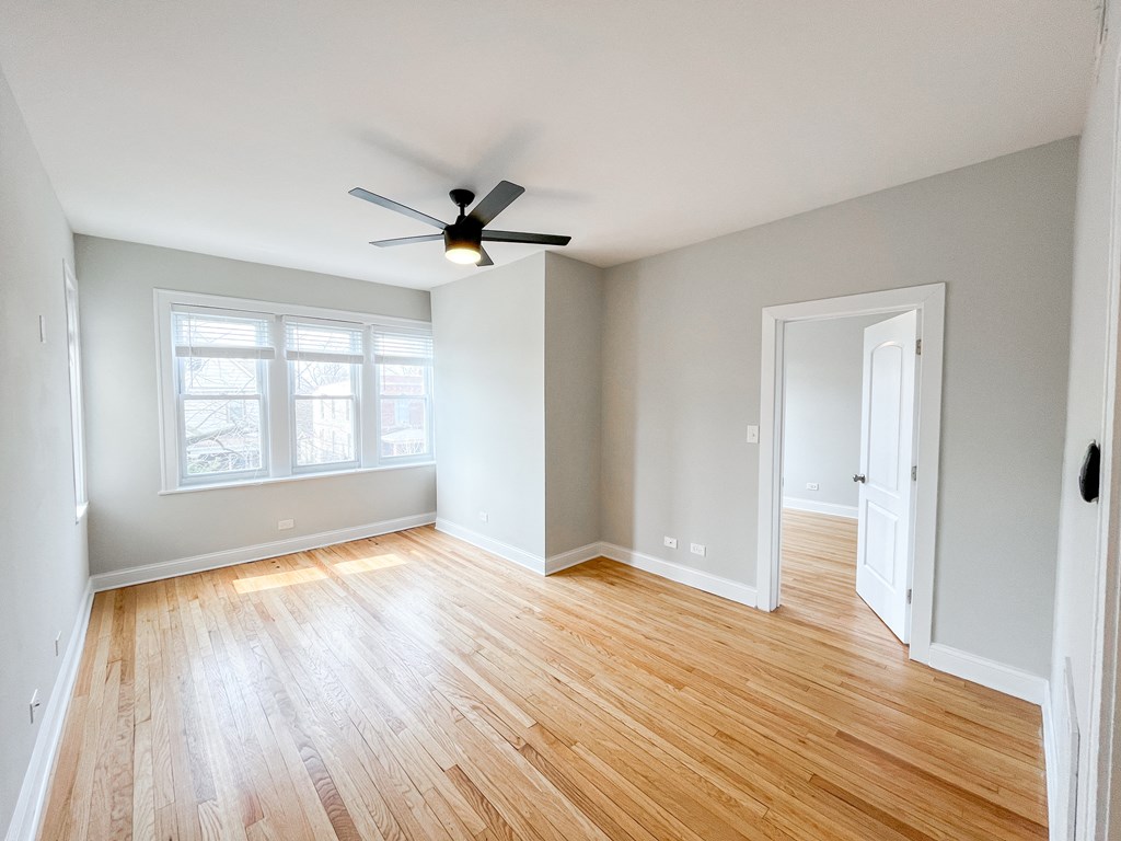 an empty living room with wood floors and a ceiling fan