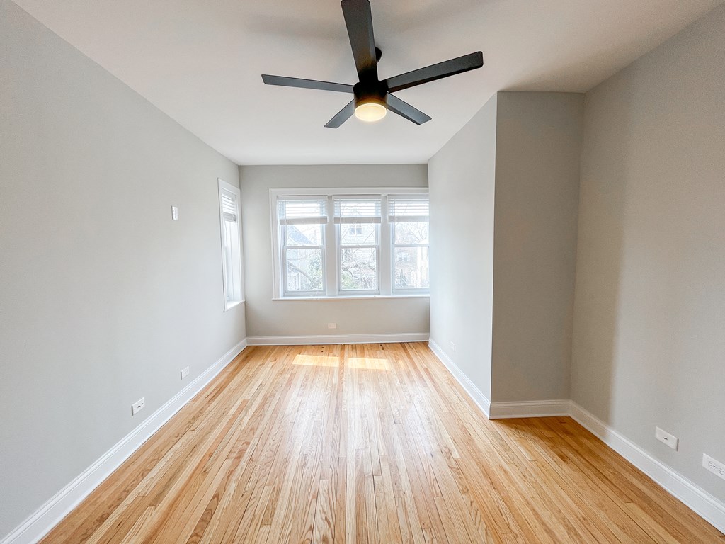 an empty living room with wood floors and a ceiling fan