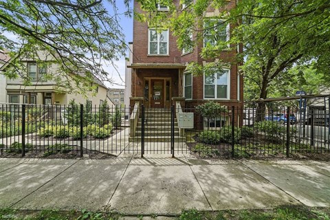 the front of a house with a gate and a sidewalk