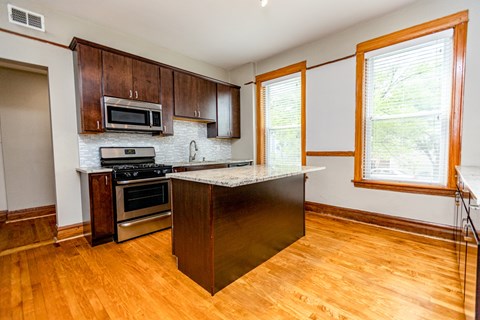 A kitchen with wooden cabinets and a black island.