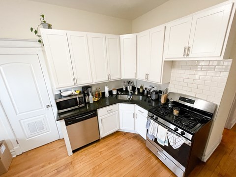 A kitchen with white cabinets and black countertops.