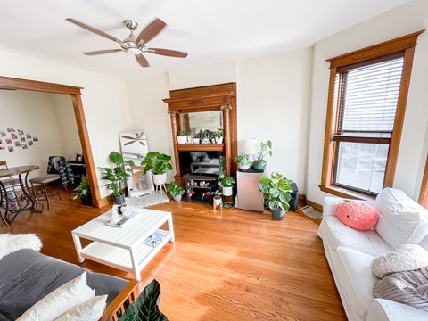 A living room with a white couch, a coffee table, and a ceiling fan.