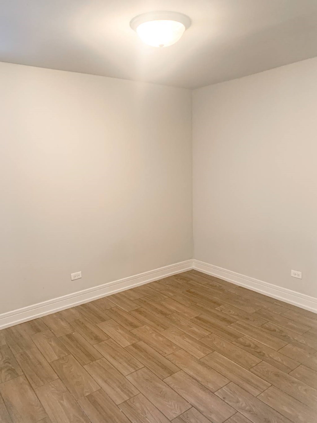 an empty room with wood flooring and white walls