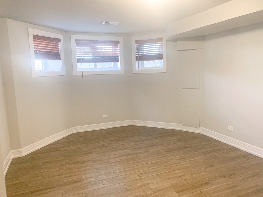 an empty room with wooden floors and three windows