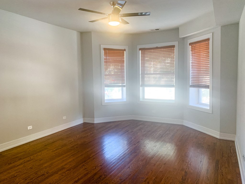 an empty living room with wood floors and a ceiling fan