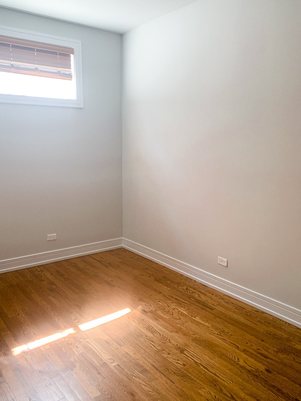 an empty room with wooden floors and a window