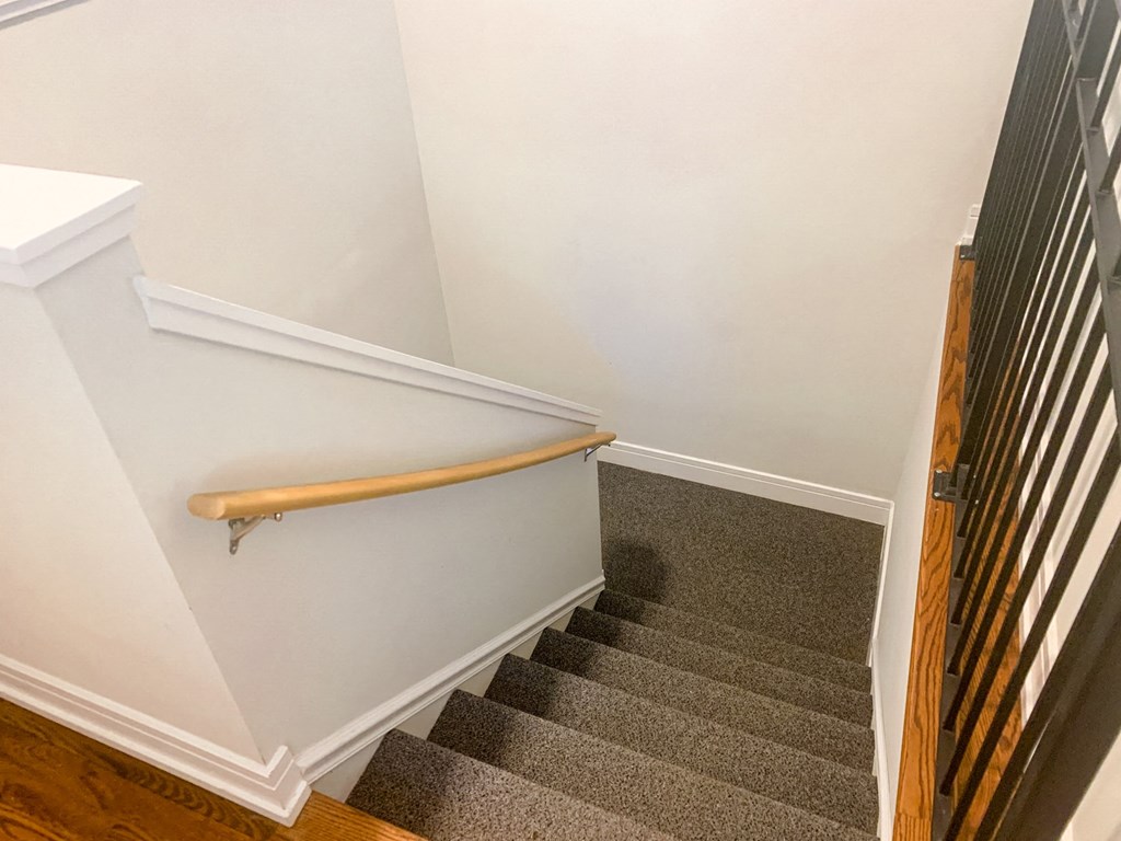 a stairway with a wooden hand rail and carpeted stairs