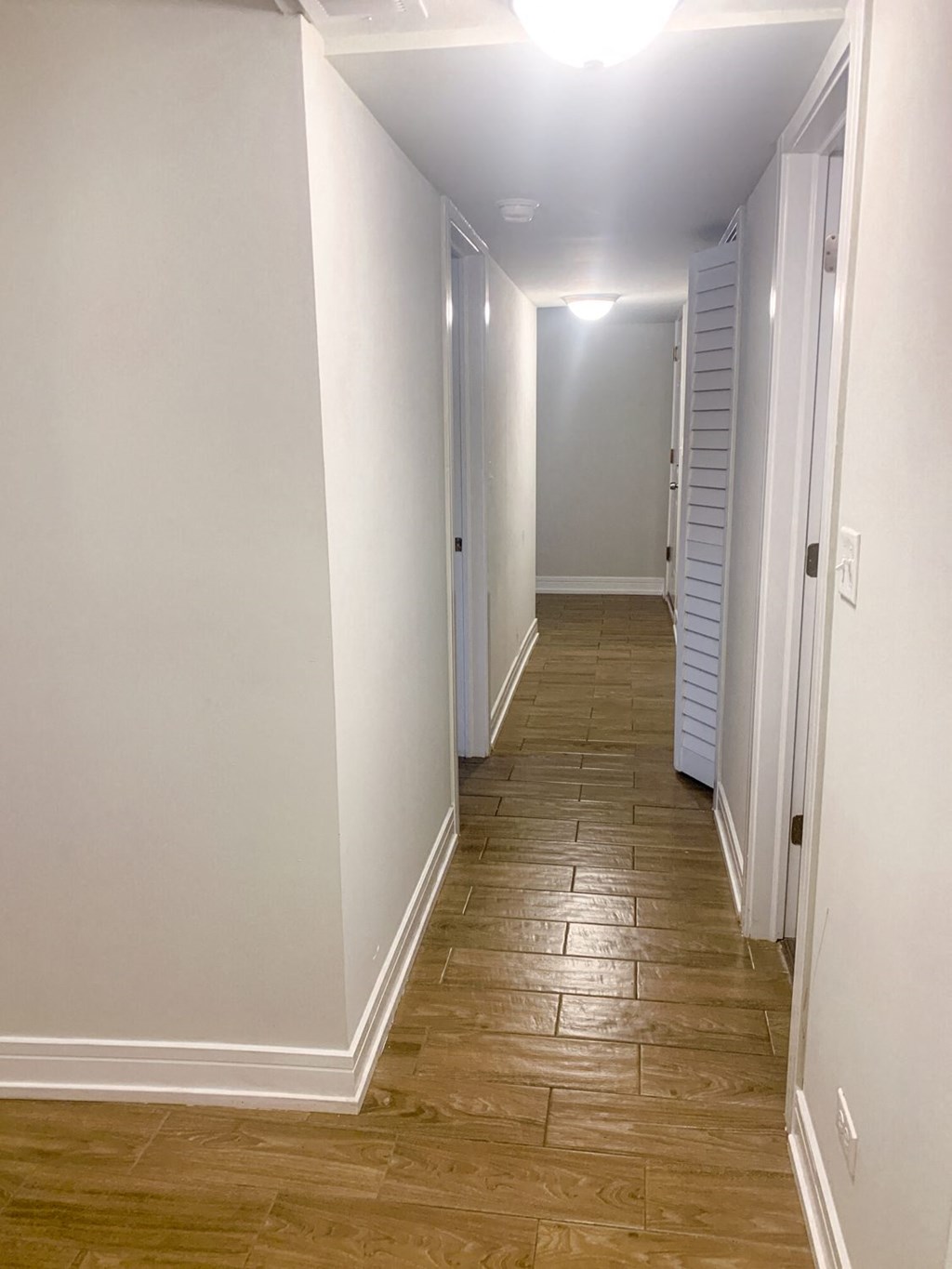 a hallway with wood flooring and white walls and white doors