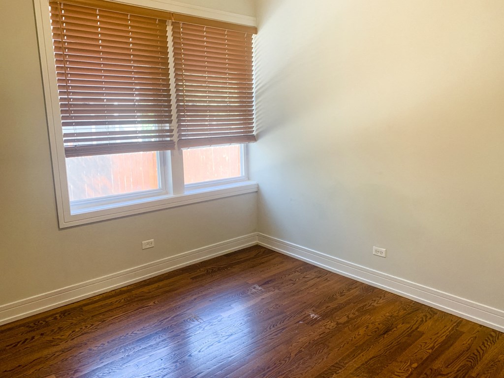 an empty room with wooden floors and two windows