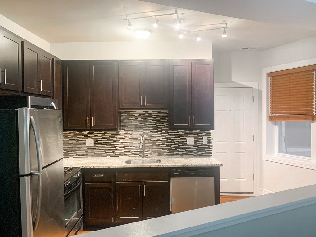 a kitchen with dark wood cabinets and a stainless steel refrigerator