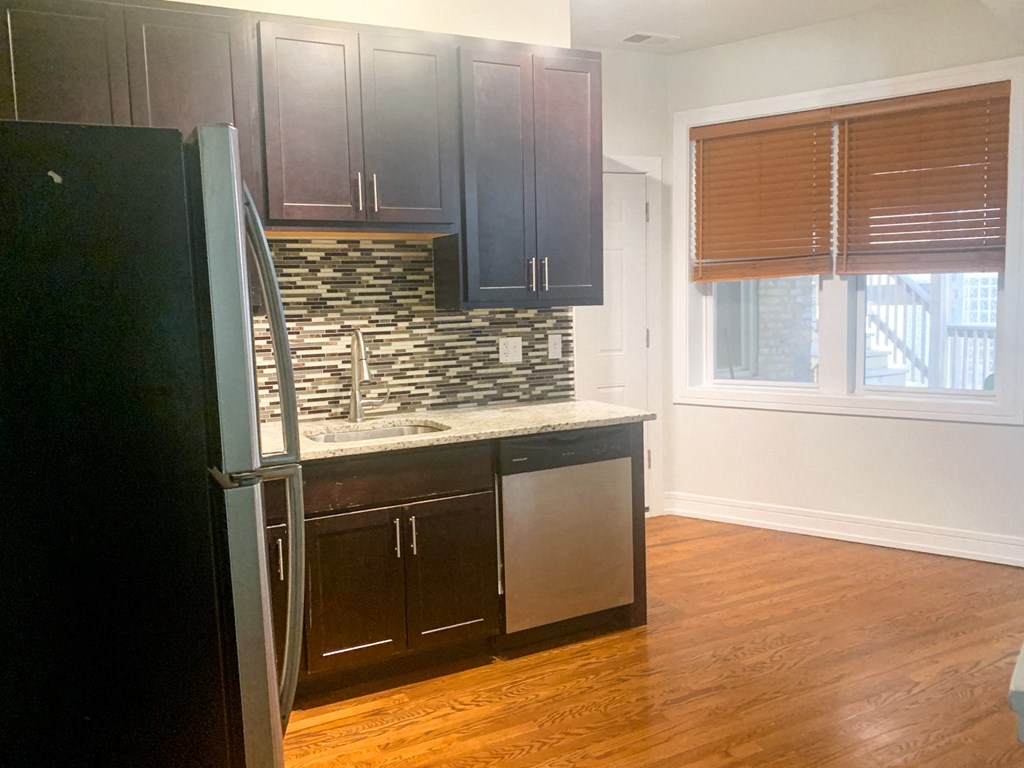 a kitchen with dark wood cabinets and a refrigerator