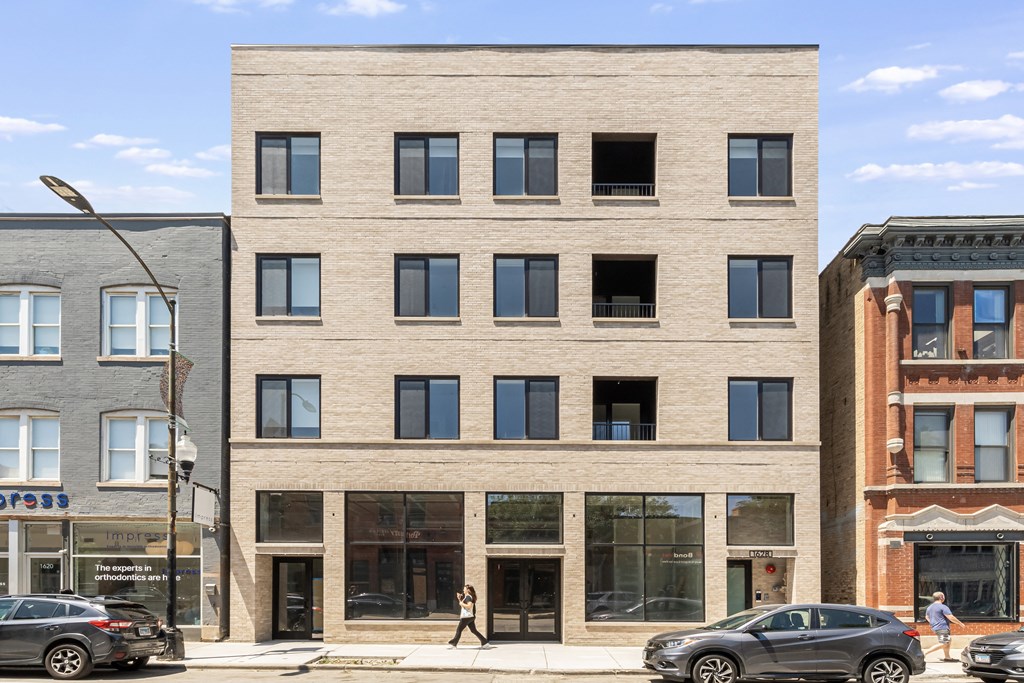 A modern building with a beige facade stands between two older buildings.