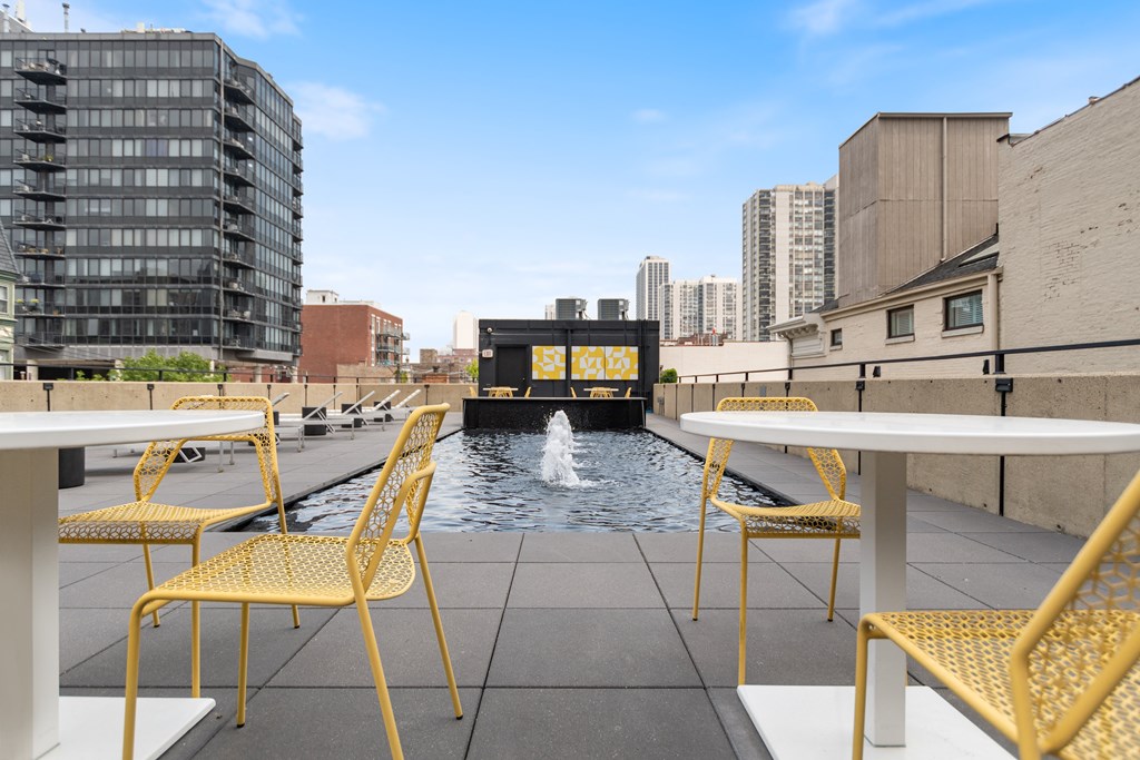 An outdoor lounge with yellow chairs and tables with the fountain at the roof of 1250 LaSalle