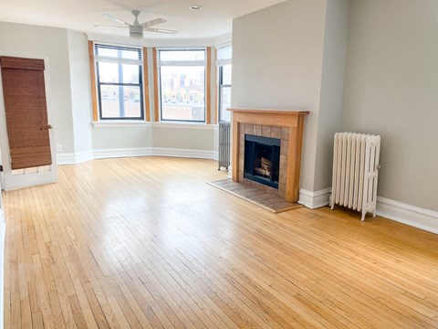 A room with a fireplace and a fan on the ceiling.
