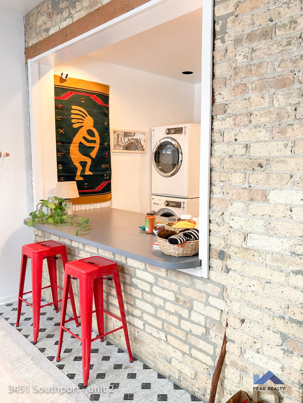 a bar with red stools in front of a brick wall with a washing machine