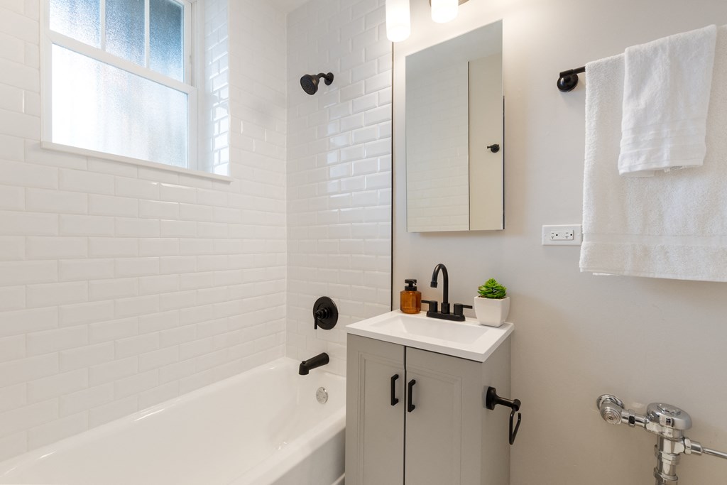 a white bathroom with a sink and a bath tub