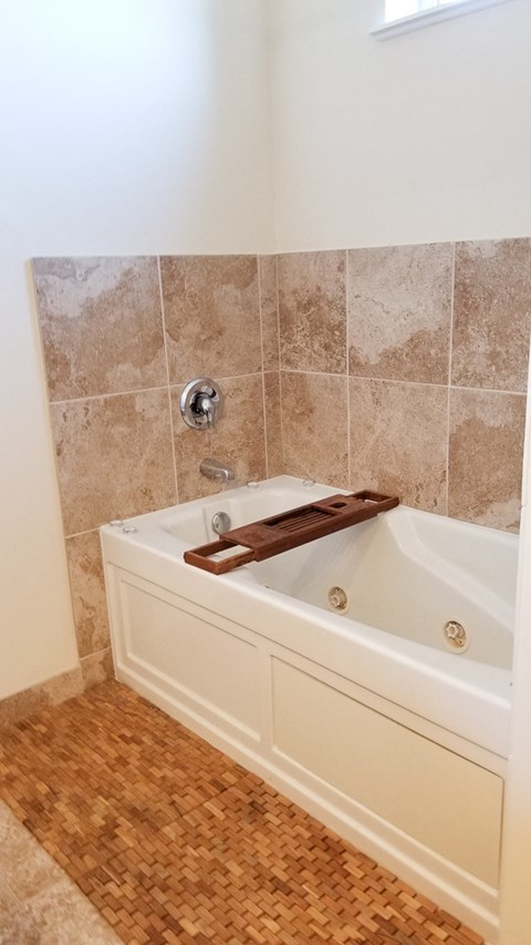 a bathroom with a tub and a shower and a wooden floor