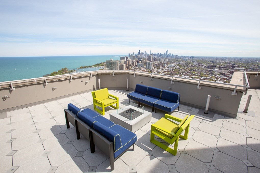 a rooftop patio with blue couches and yellow chairs and a view of the city