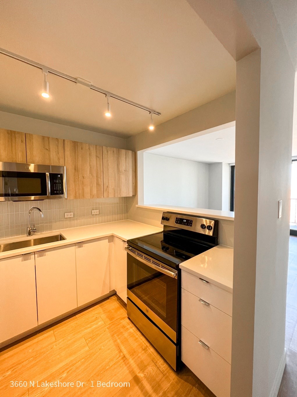 an empty kitchen with white cabinets and stainless steel appliances
