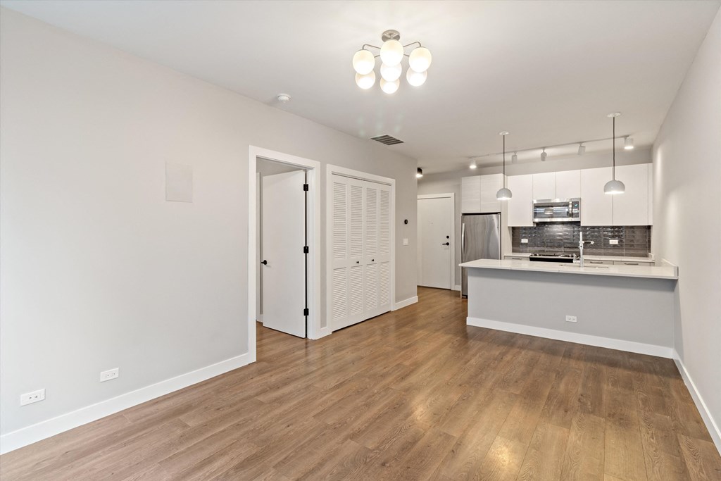 a living room and kitchen with white walls and wood floors