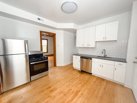 A kitchen with a stainless steel refrigerator and wooden floors.