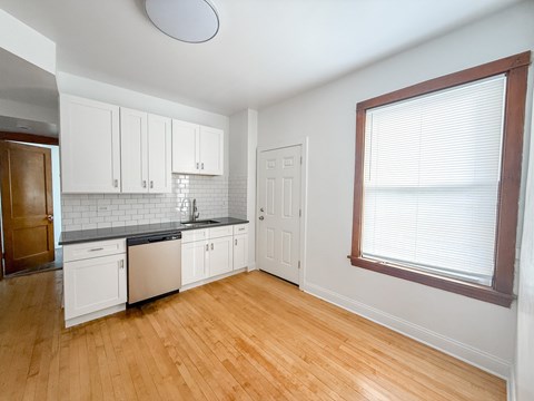 A kitchen with white cabinets and a wooden floor.