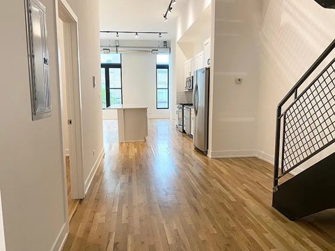 A long hallway with a wooden floor and a black metal staircase.